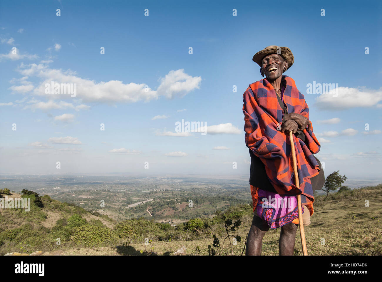 Un tradizionale sambuco Masai sorrisi sulla cima di una collina con una vista panoramica del Kenya in background. Kenya, Africa. Foto Stock