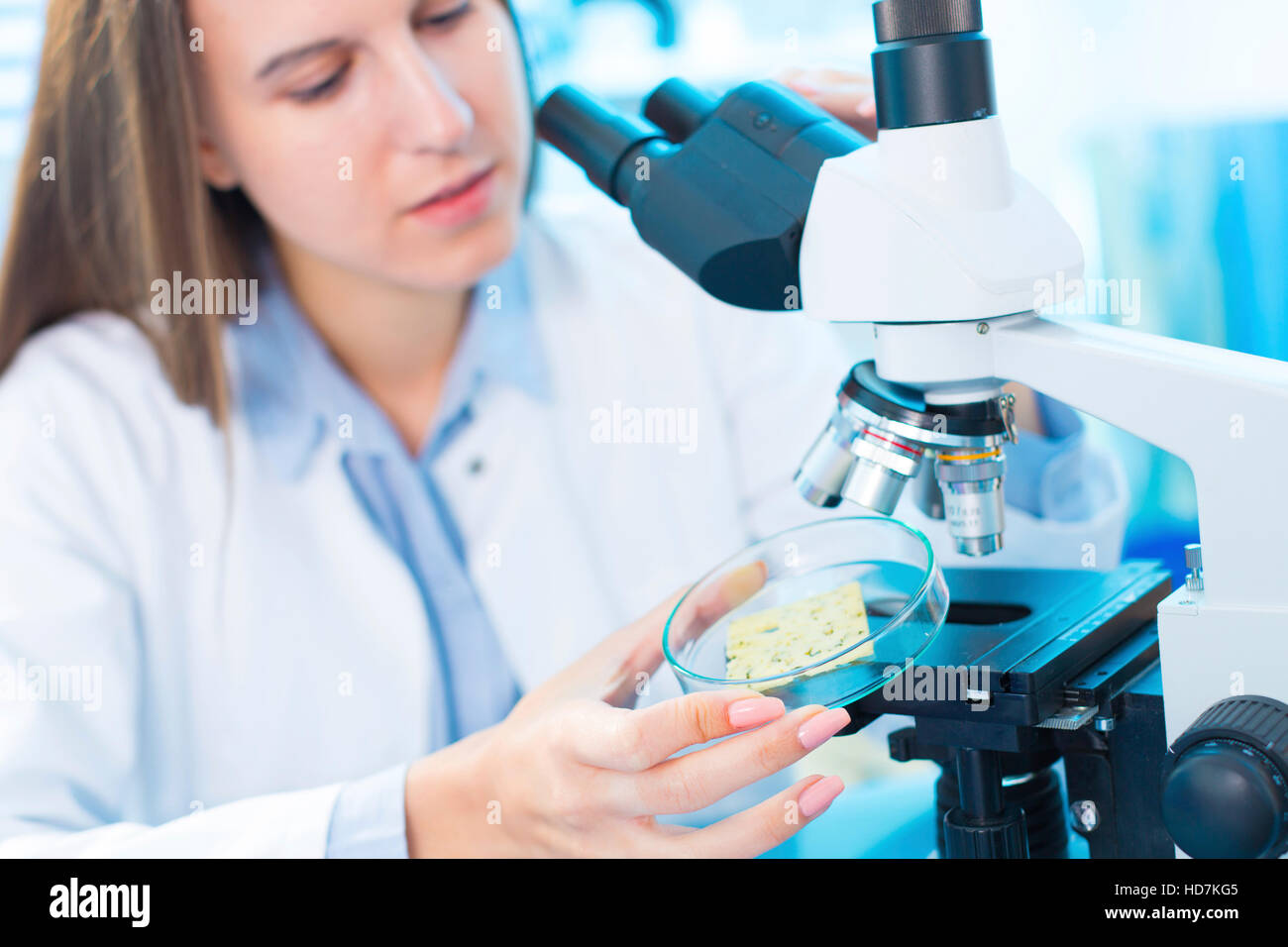 Modello rilasciato. Giovane donna test cibo sotto microscopio in alimenti laboratorio di controllo qualità. Foto Stock