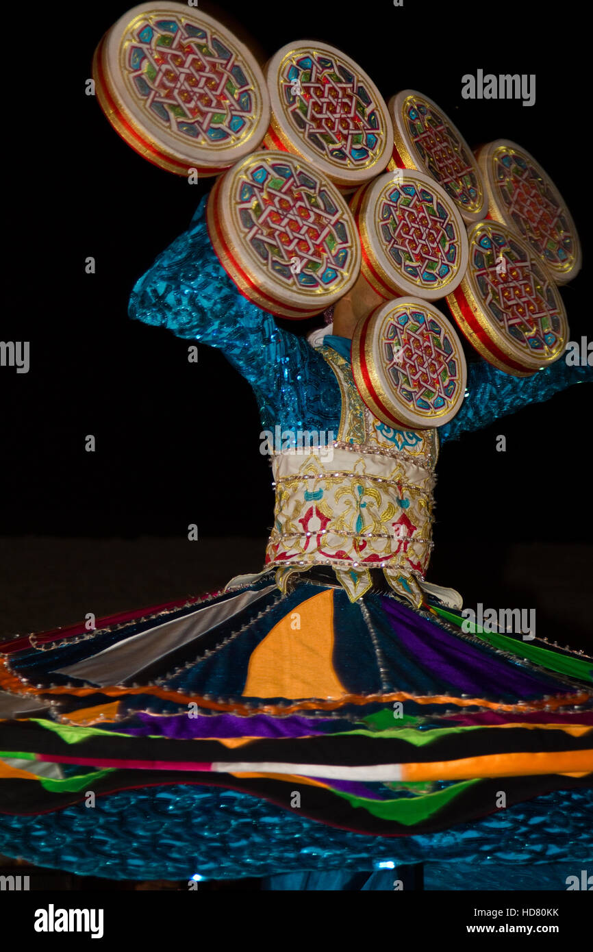 Un cittadino locale di eseguire la tradizionale danza folk di notte come parte di un safari nel deserto esperienza di campo in Dubai EMIRATI ARABI UNITI Foto Stock