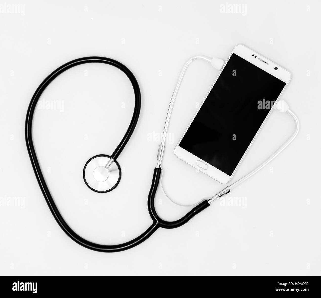 Stetoscopio medico utensile sopra la superficie di un mobile smart phone, composizione isolata su sfondo bianco Foto Stock