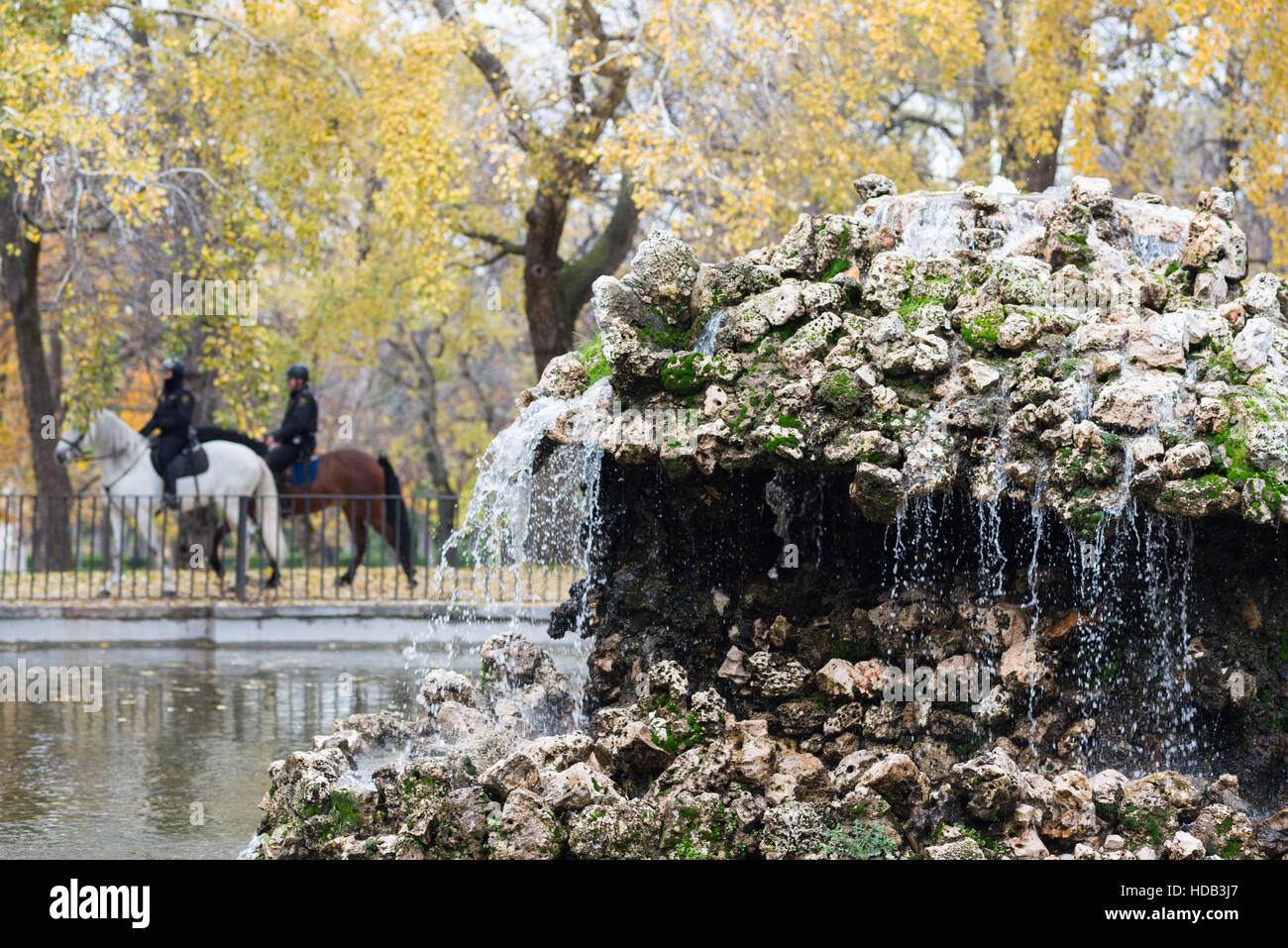 Fontana nel parco del Retiro di Madrid in Spagna con due cavalli della polizia di passaggio. Foto Stock