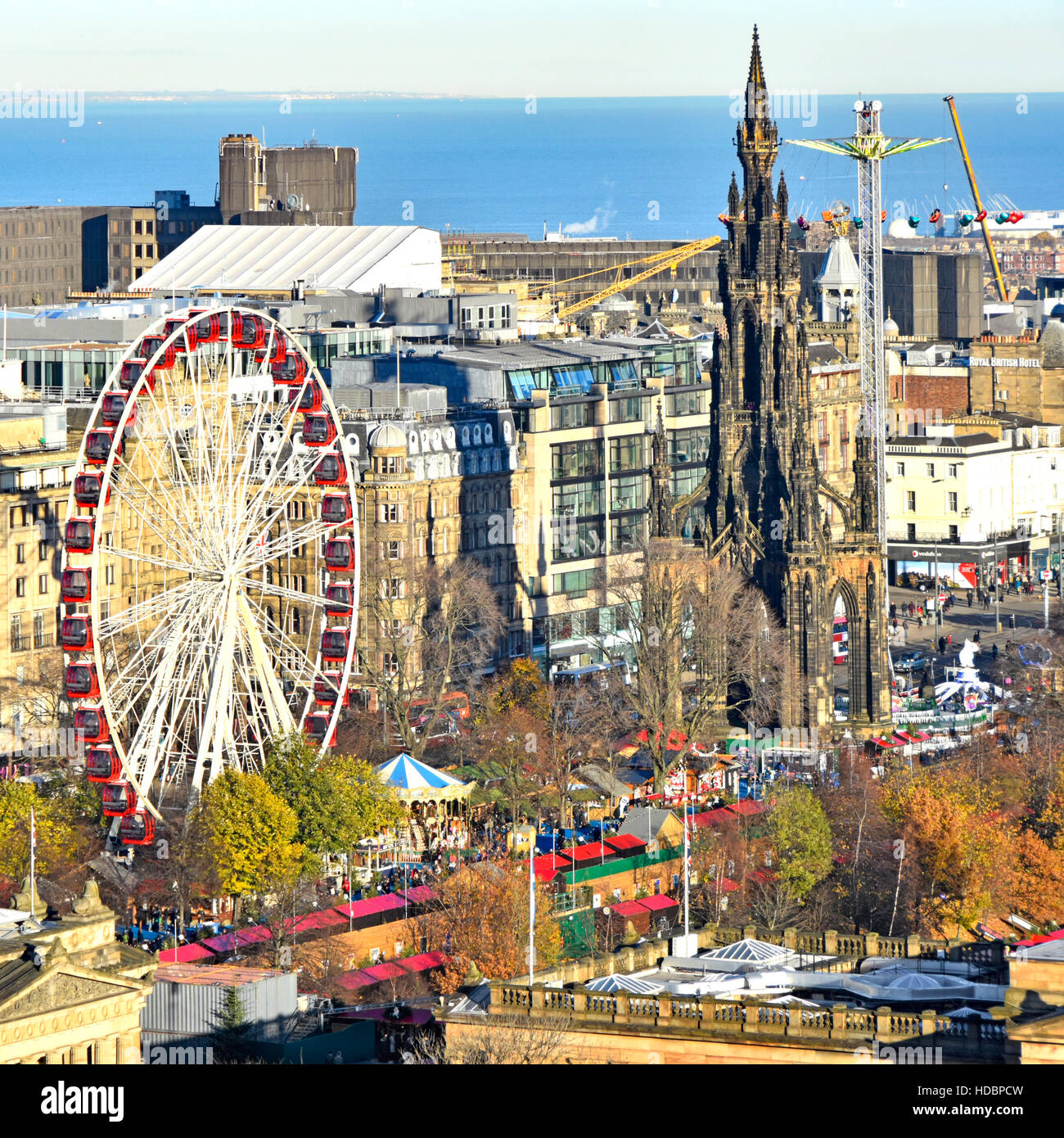 Scozia uk europeo di Edimburgo il Mercato di Natale & Ferris fairground ride a est di Princes Street Gardens Monumento di Scott Scottish Firth of Forth distante Foto Stock