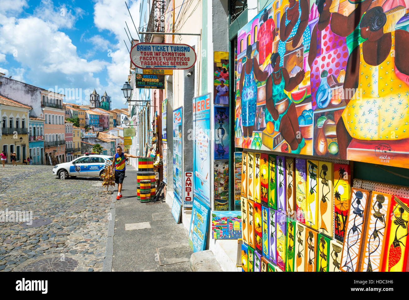 SALVADOR, Brasile - MARZO 12, 2015: un venditore ambulante si erge al di fuori di negozi che vendono Afro-brasiliano souvenir turistici nel Pelourinho. Foto Stock