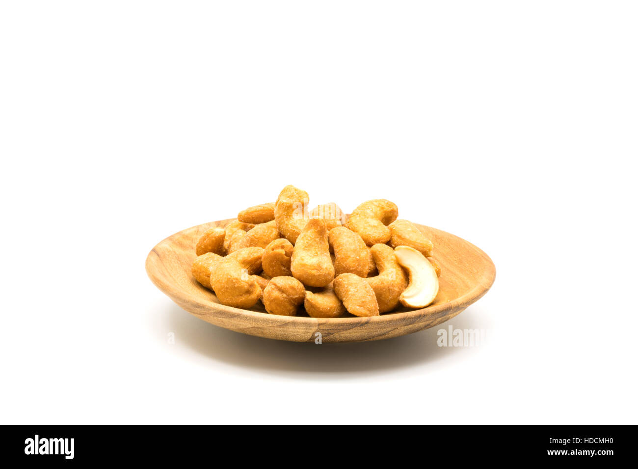 Arrosto di salato noci di anacardio in un piatto di legno su sfondo bianco Foto Stock