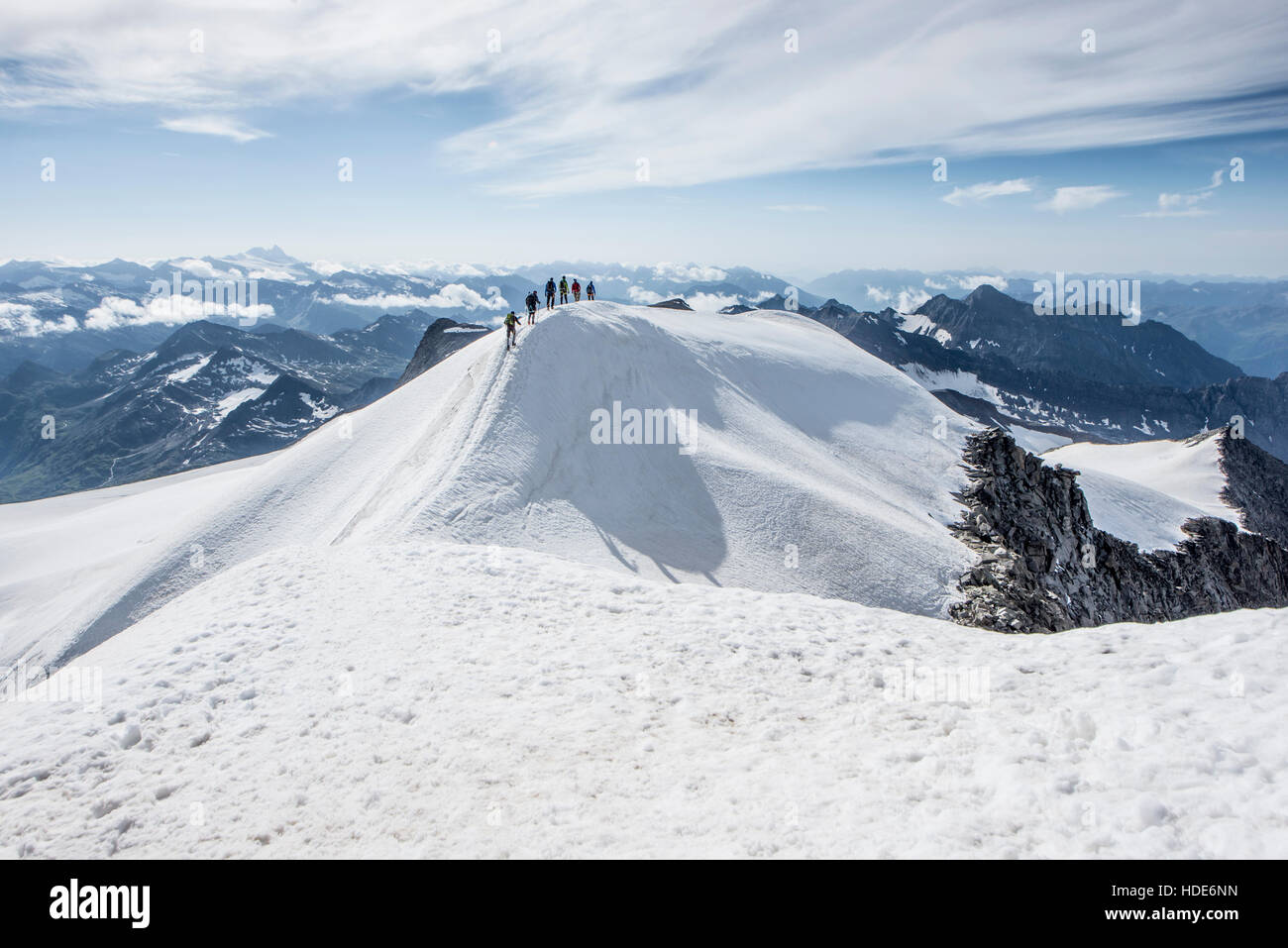 Un gruppo di alpinisti cordata insieme la scalata al pendio nevoso della montagna, il ghiacciaio e il panorama dei picchi in background Foto Stock