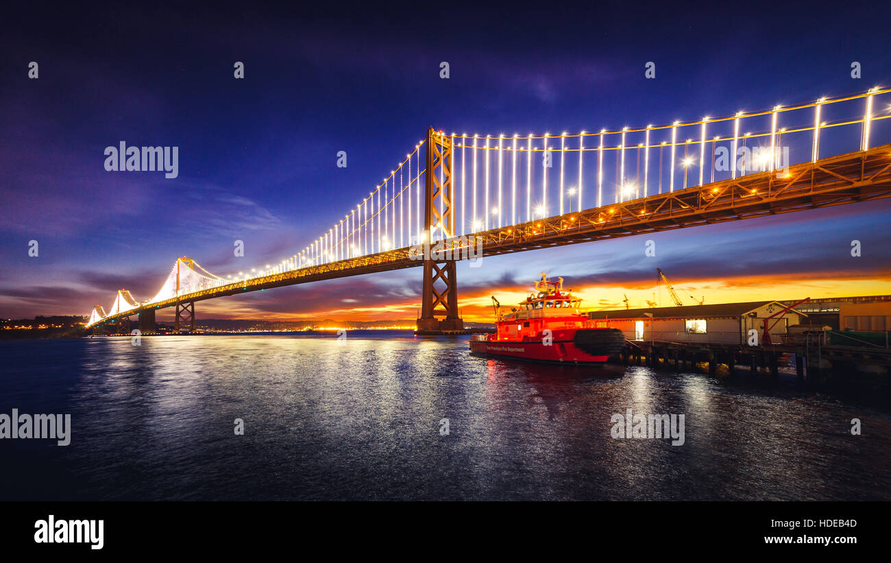 San Francisco Oakland Bay Bridge illuminata di sunrise, California Foto Stock