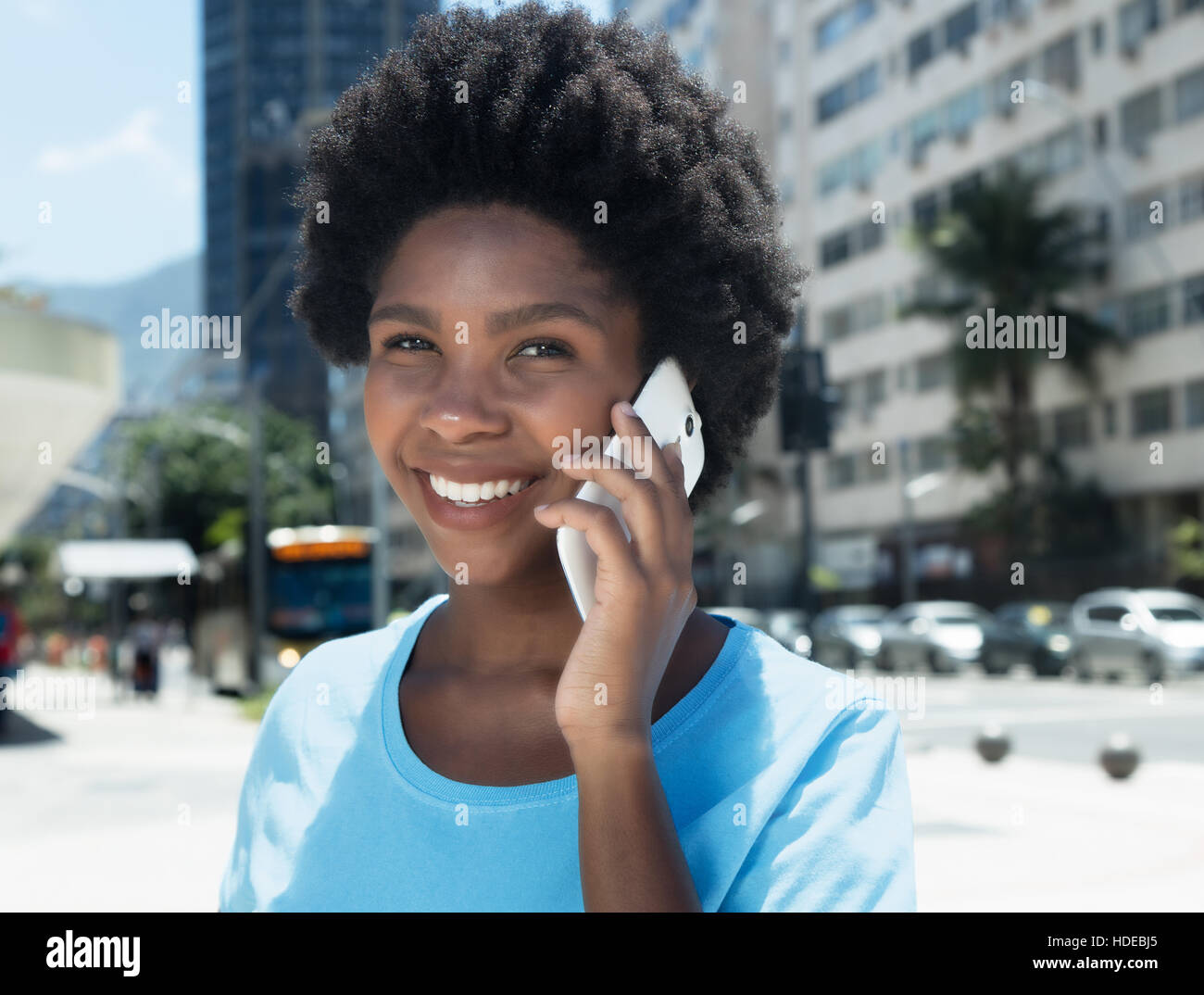 Felice African American Girl con un telefono cellulare all'aperto nella città in estate Foto Stock