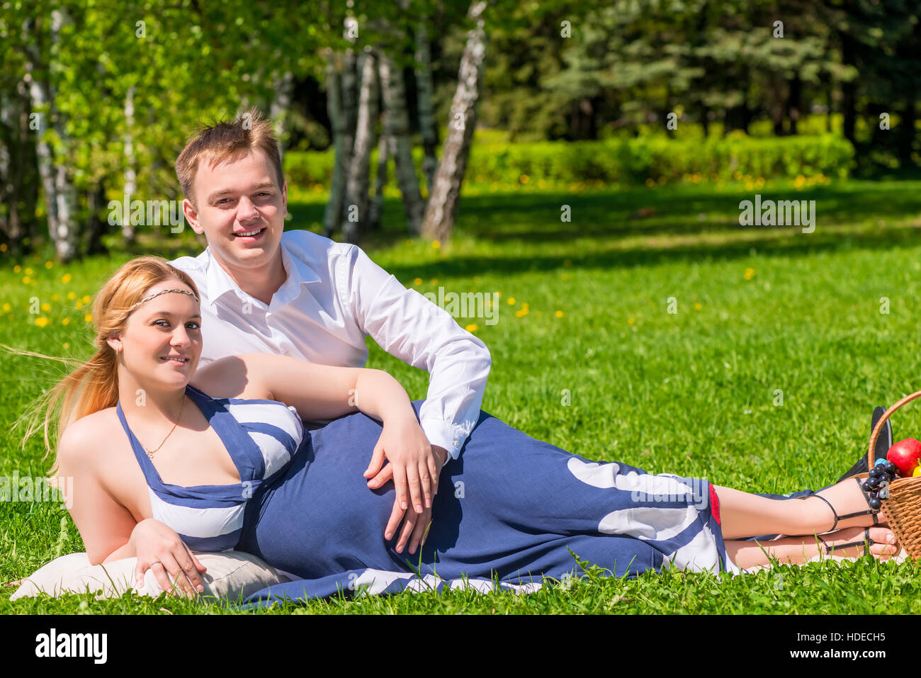 La famiglia felice coppia in gravidanza in estate il parco su un picnic Foto Stock