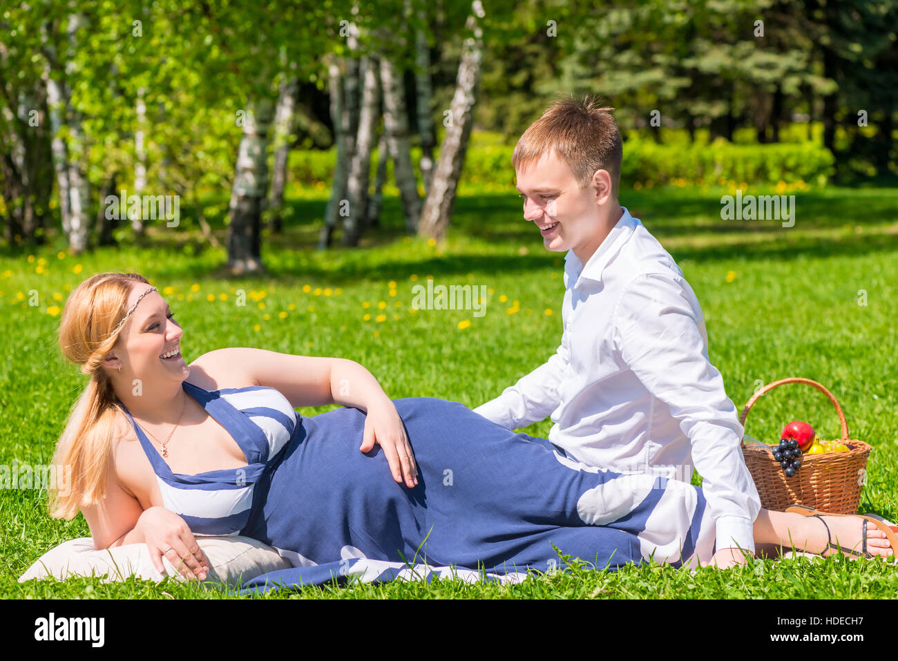 Giovane coppia in gravidanza in una giornata di sole e rilassarsi sul prato Foto Stock
