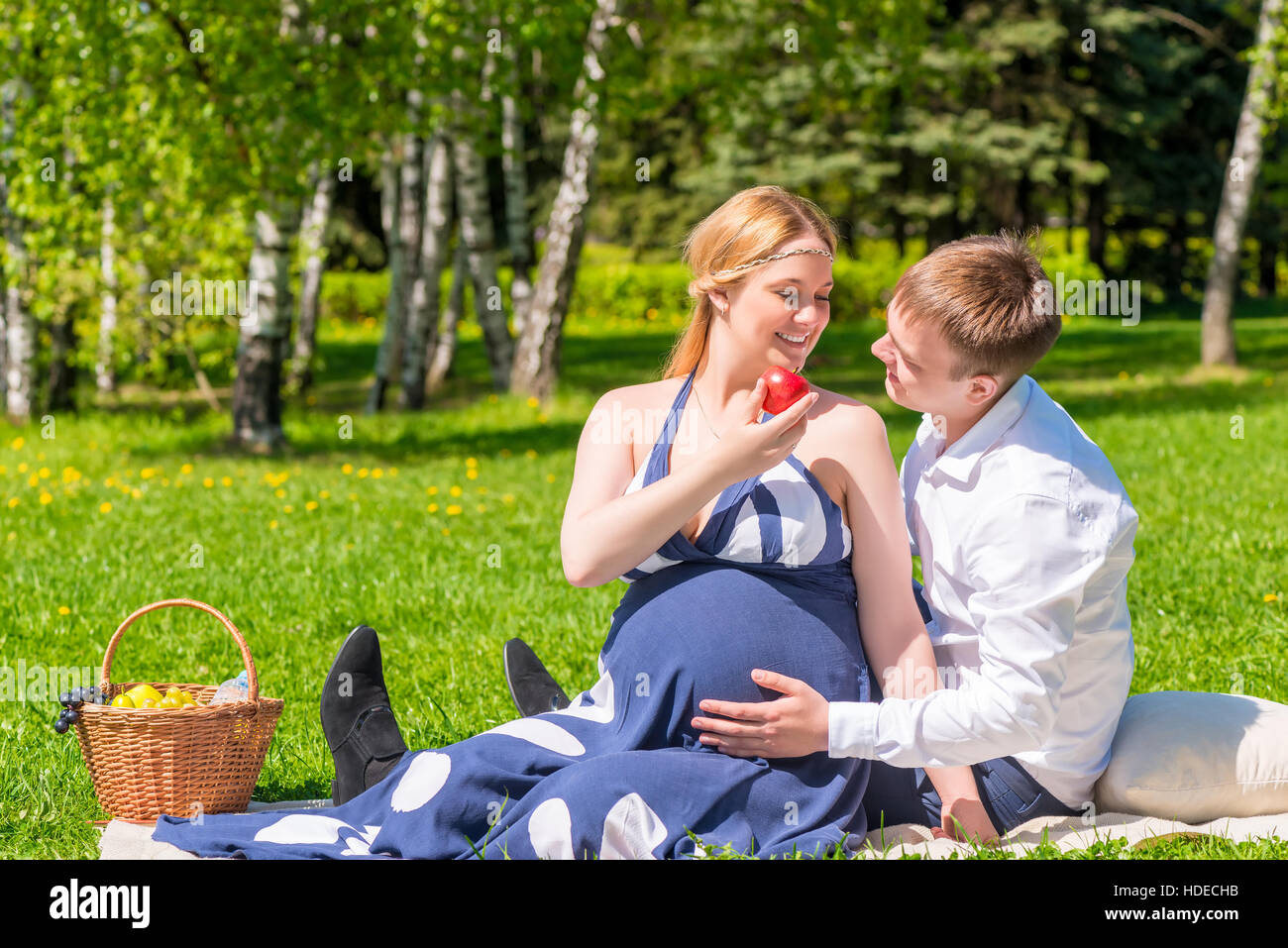 Coppia giovane avente un picnic in un parco della città, una donna è in attesa di un bambino Foto Stock