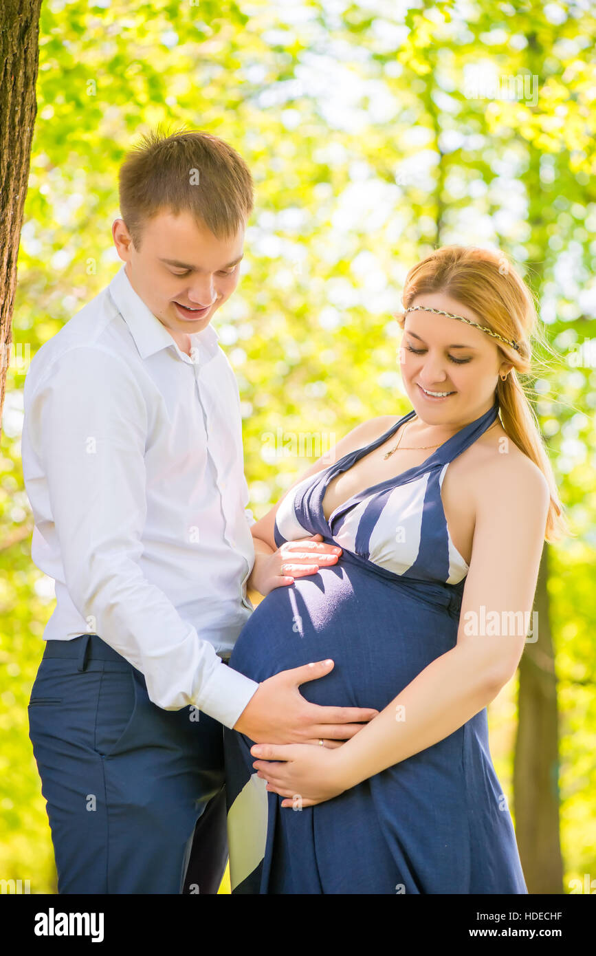 Caring papà strofinarsi il ventre di una moglie incinta nel parco Foto Stock