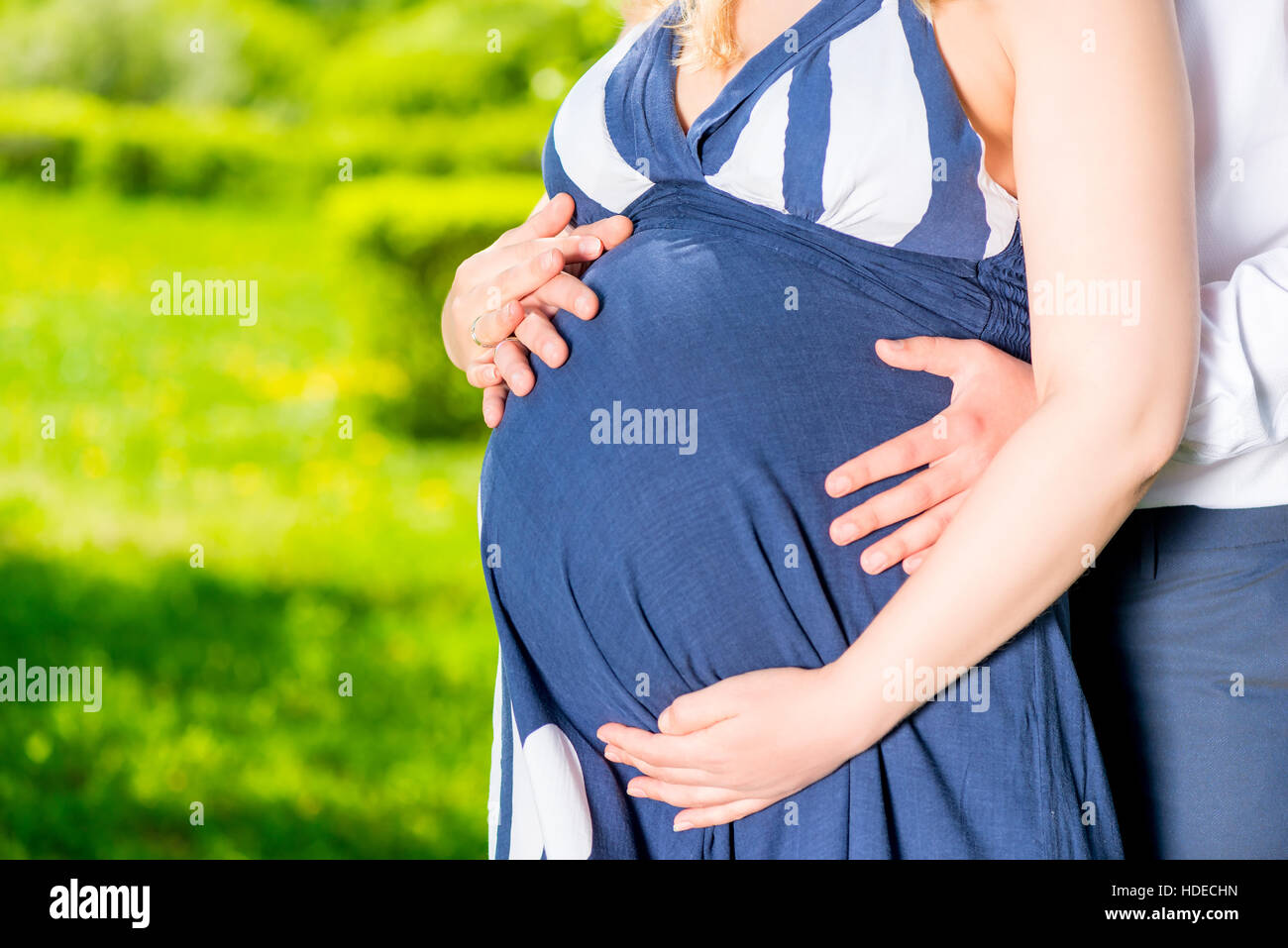 La pancia di una donna in stato di gravidanza tra le braccia di un uomo che amava closeup Foto Stock