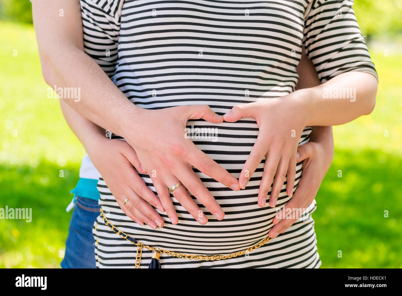 Gravidanza la pancia e le mani in una forma di cuore sul ventre madre in attesa Foto Stock