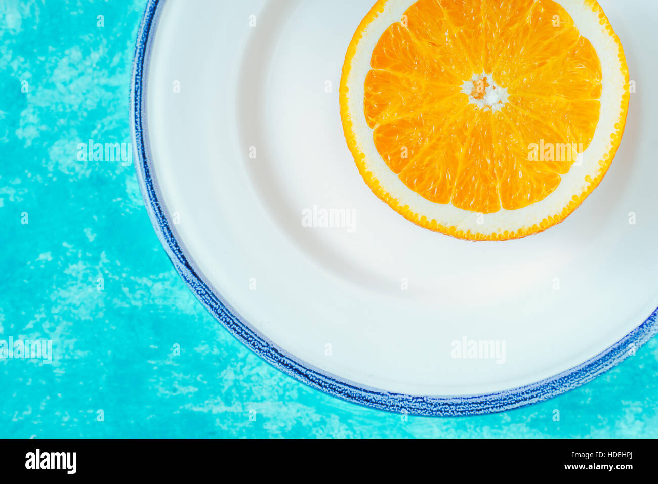 La metà di colore arancione sulla piastra bianca su sfondo ciano in orizzontale Foto Stock