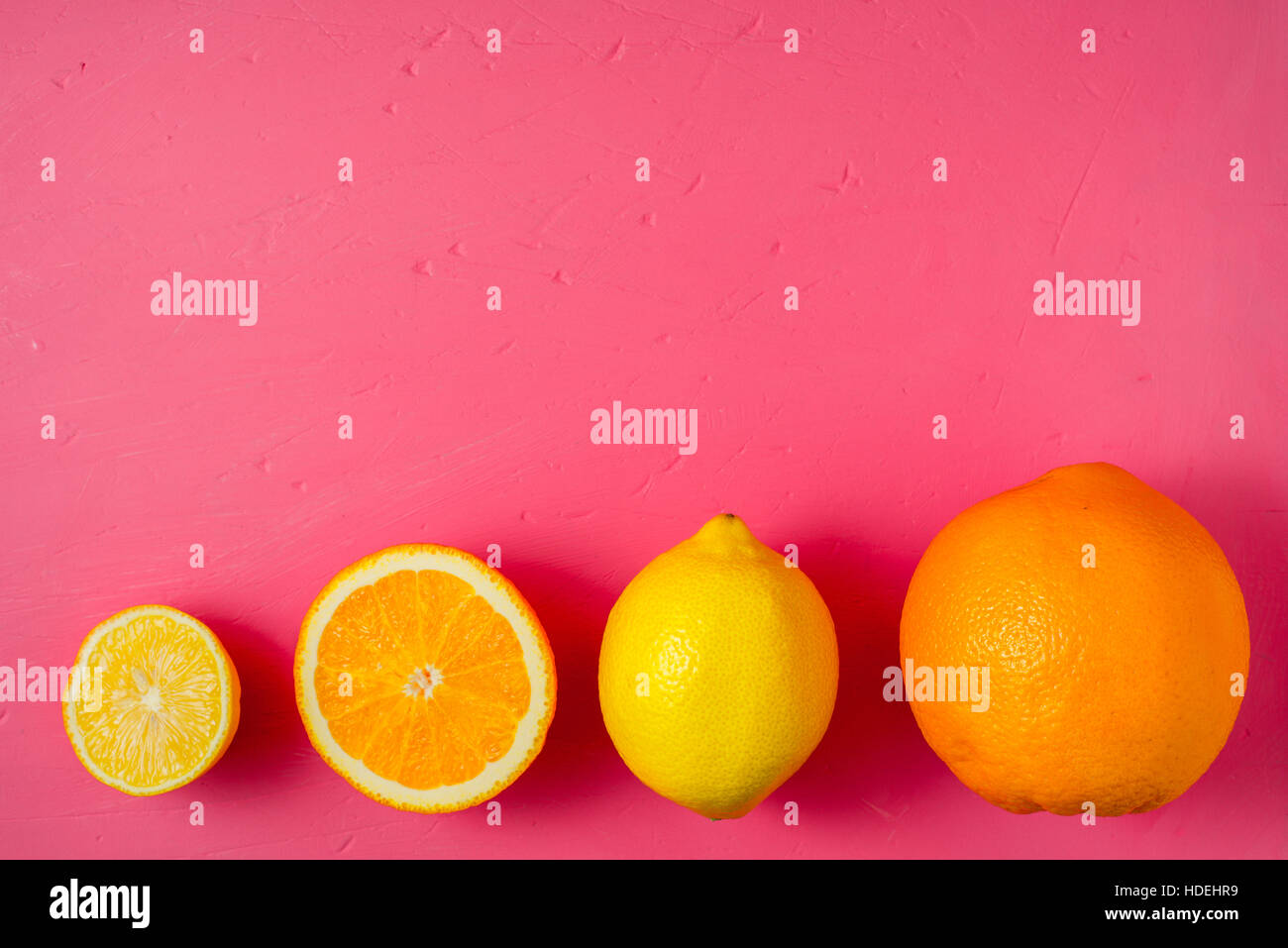 I limoni e le arance sul luminoso sfondo rosa Foto Stock