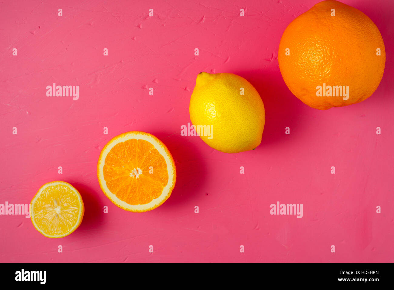 I limoni e le arance sul luminoso sfondo rosa vista superiore Foto Stock