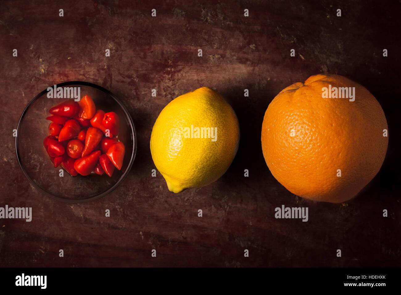 Arancio, limone e pepe caldo sul buio sfondo rosso Foto Stock