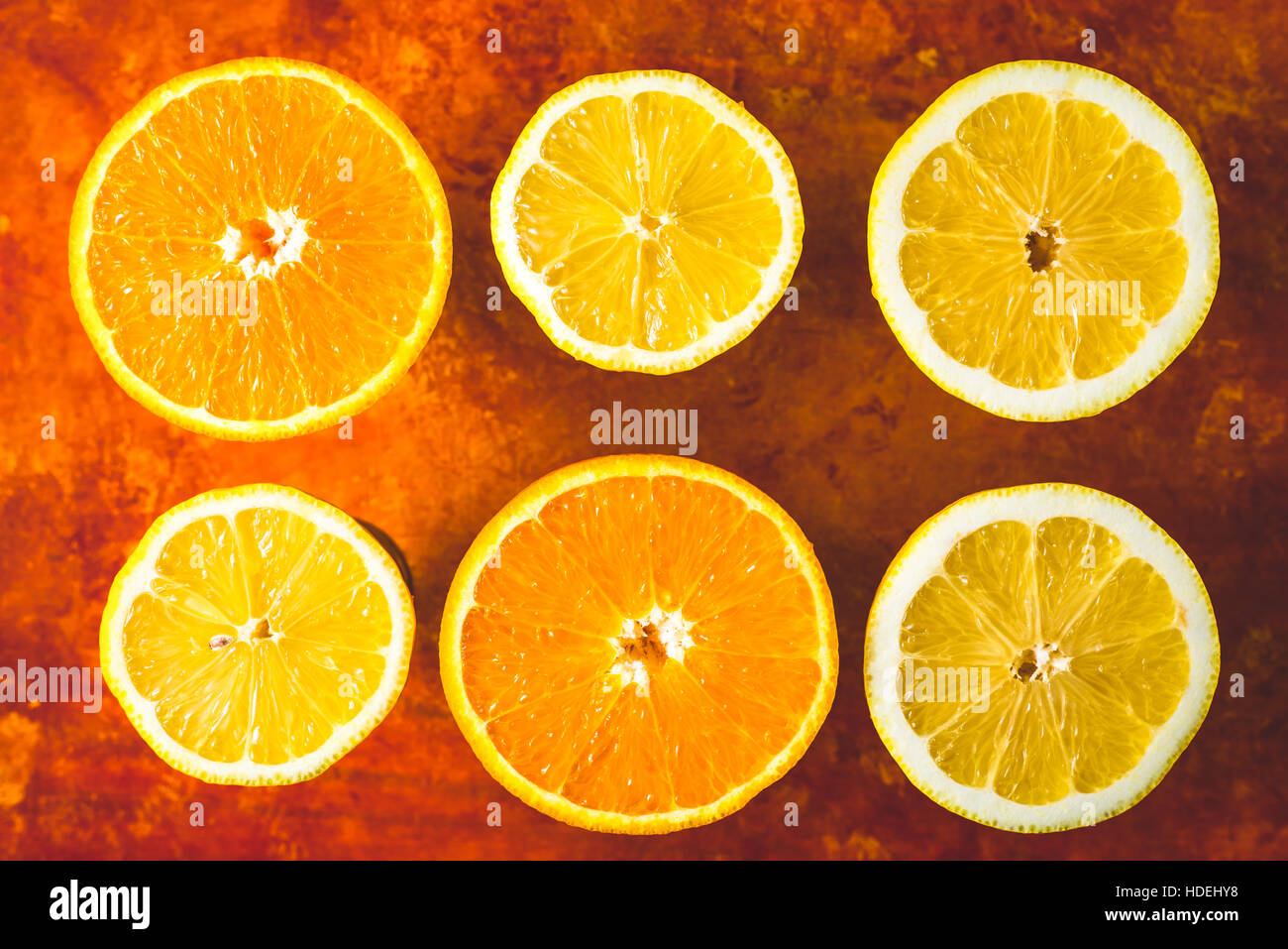 Limone e fettine di arancia sullo sfondo di terracotta vista superiore Foto Stock