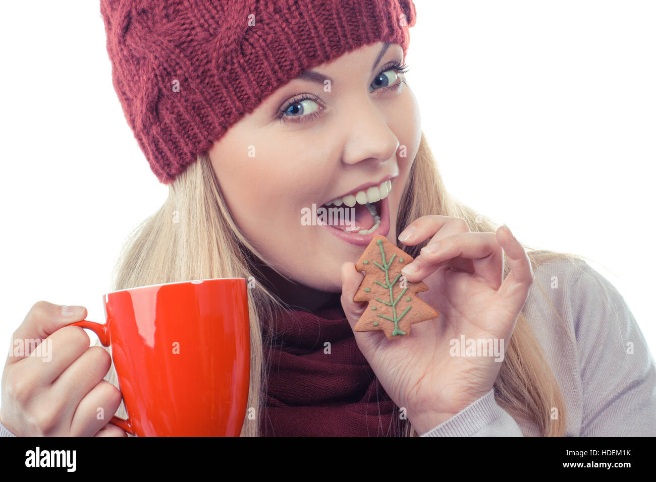 Foto d'epoca, donna sorridente indossando cappello di lana e scialle, tenendo gingerbread o cookie di festosa e rosso tazza di tè caldo, sfondo bianco Foto Stock