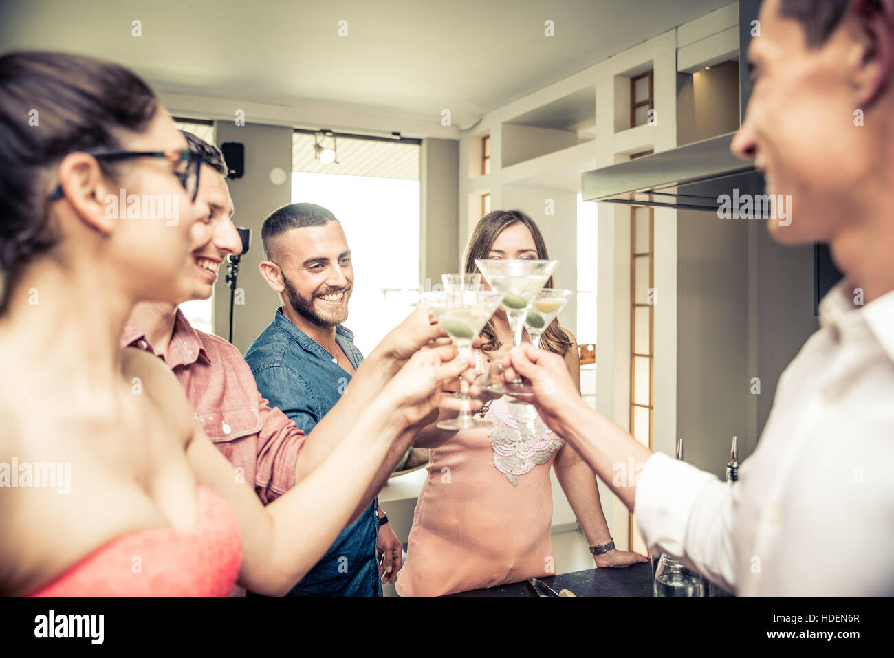 Gruppo di amici avente parte a casa e tostatura bicchieri da cocktail Foto Stock