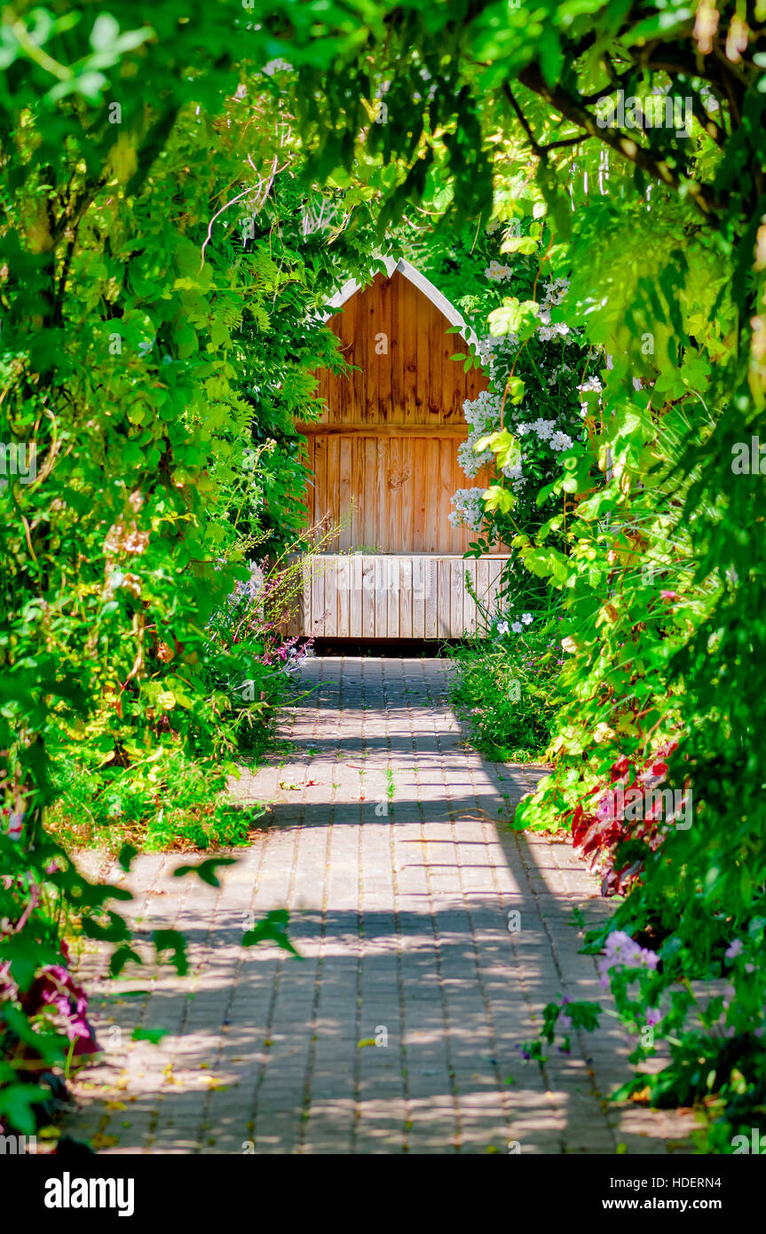Giardino passerella trellis nascondiglio nascosto seduta tranquilla area banco vuoto all'aperto ombreggiata da vigna e rose Foto Stock