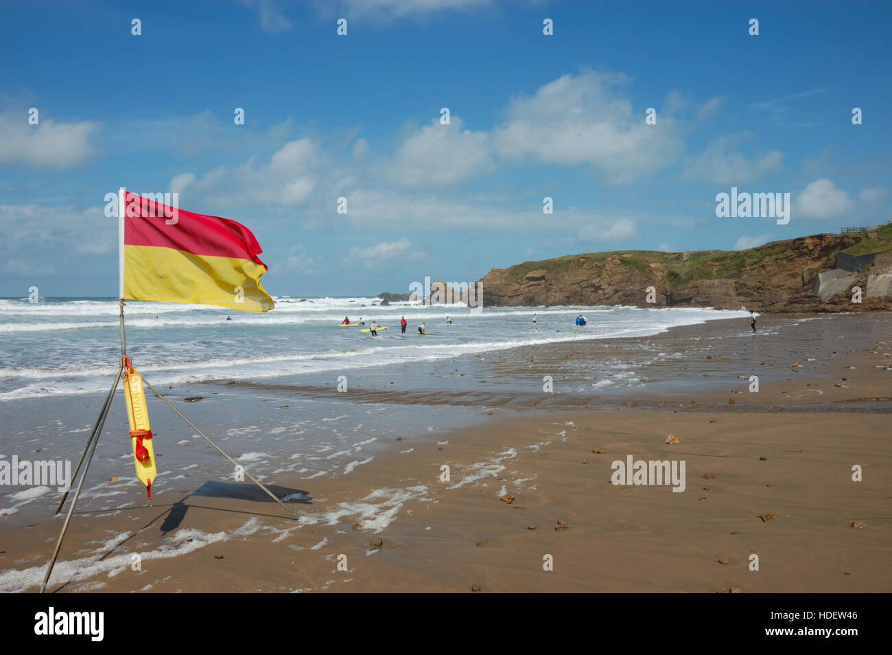 Un rosso e giallo RNLI spiaggia bandiera di sicurezza a volare su Crooklets Beach che denota una zona sorvegliata da bagnini. Foto Stock