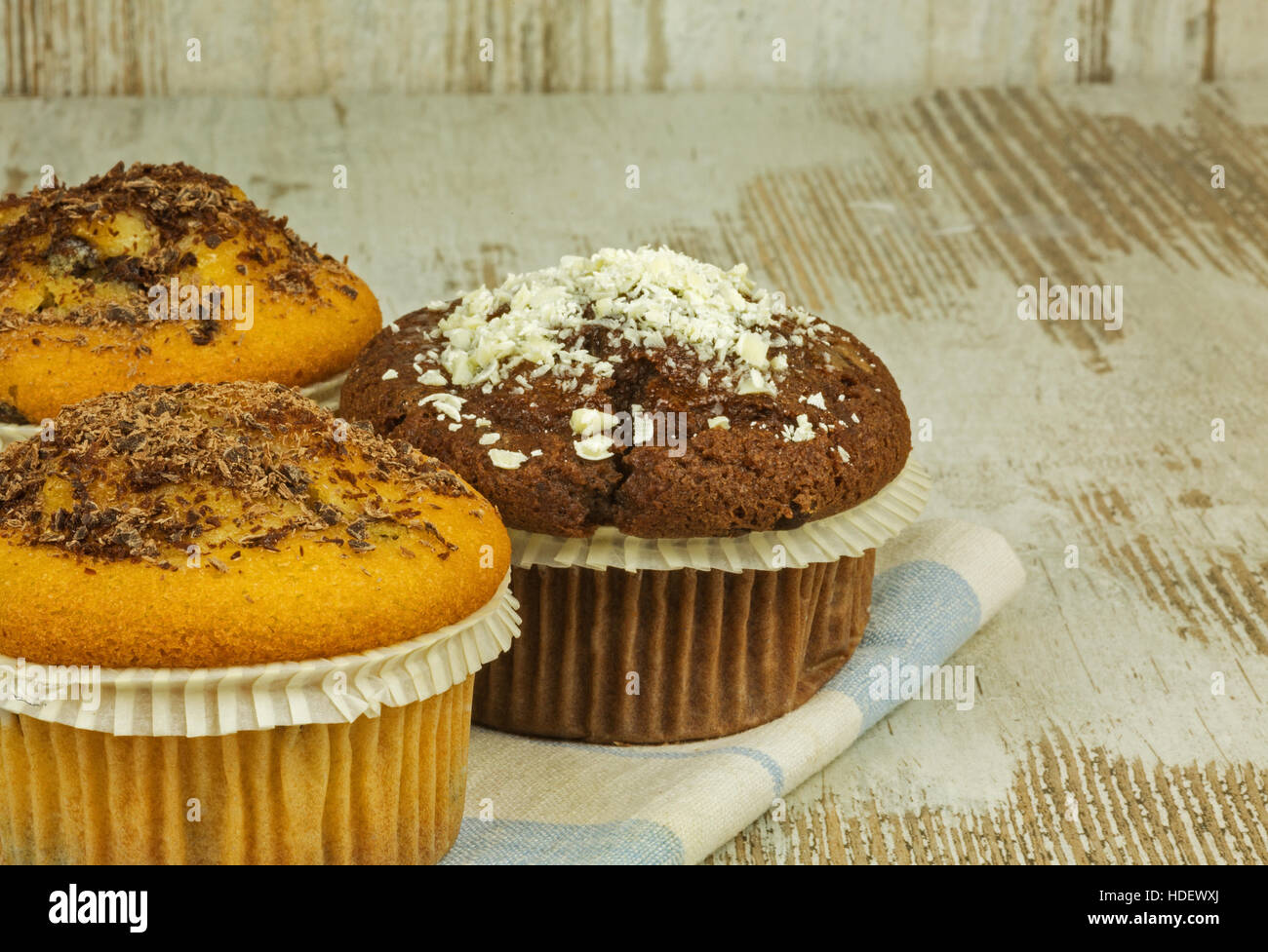 Due di spugna e un muffin di cacao e rabboccato con bianco e scuro torta al cioccolato su una vecchia cucina in legno tavolo. Messa a fuoco selettiva .chiudere, vista orizzontale. Foto Stock