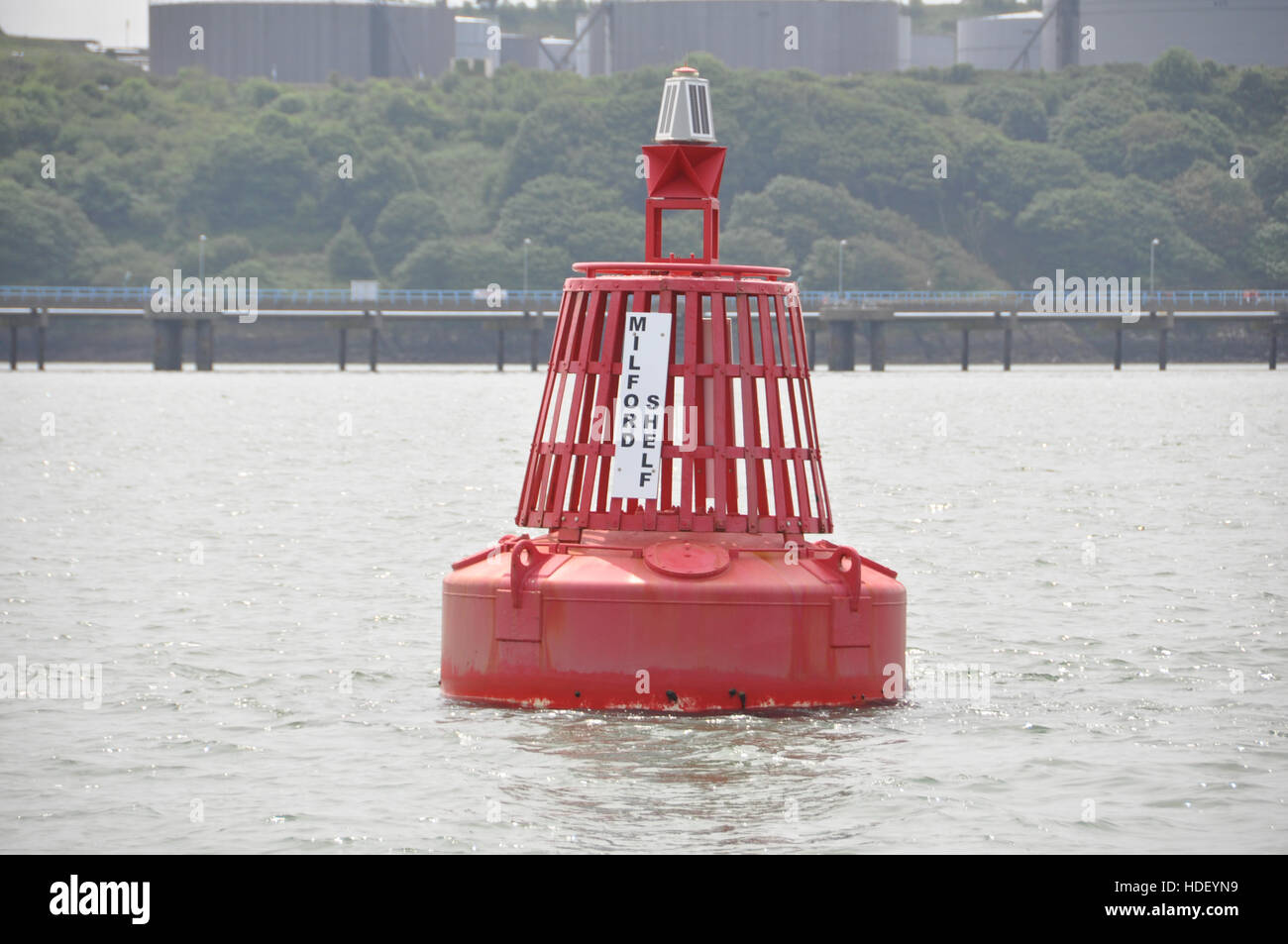 Milford ripiano porta boa di navigazione con terminale petrolifero jetty dietro. Foto Stock