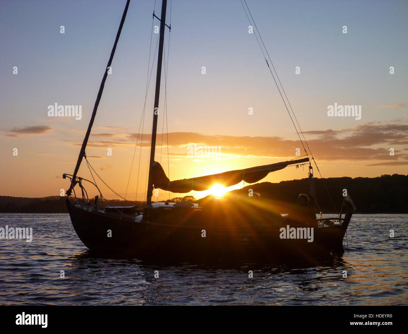 Piccola barca motoring in acqua calma con il sole che tramonta dietro. Foto Stock