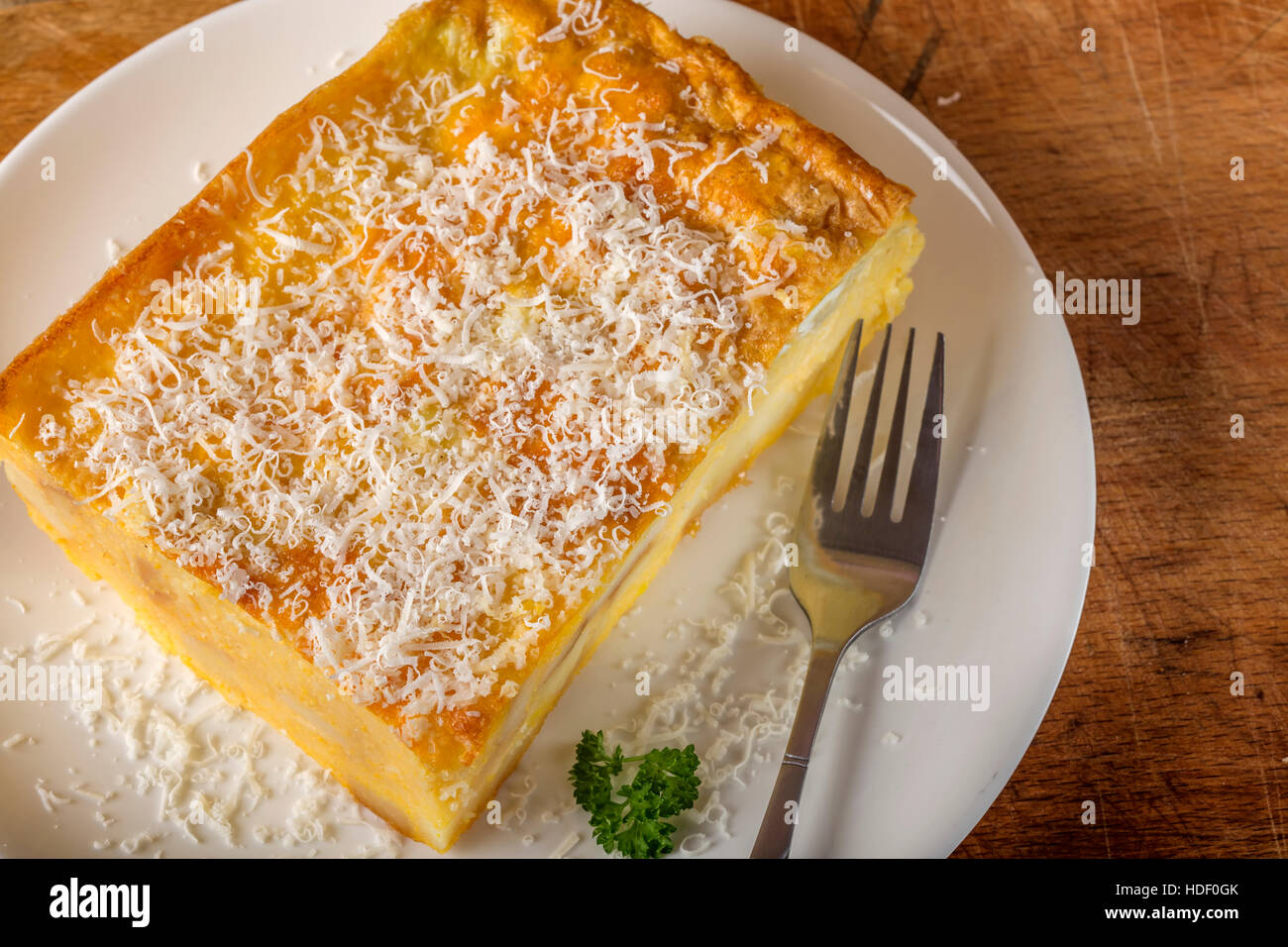 Polenta al forno con patate e formaggio e uova fracassato sulla piastra con forca Foto Stock