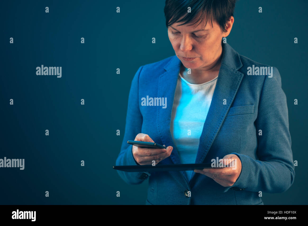 Smartphone e Tablet sincronizzazione dati, imprenditrice la sincronizzazione di file e documenti su wireless dei dispositivi elettronici in ufficio business Foto Stock