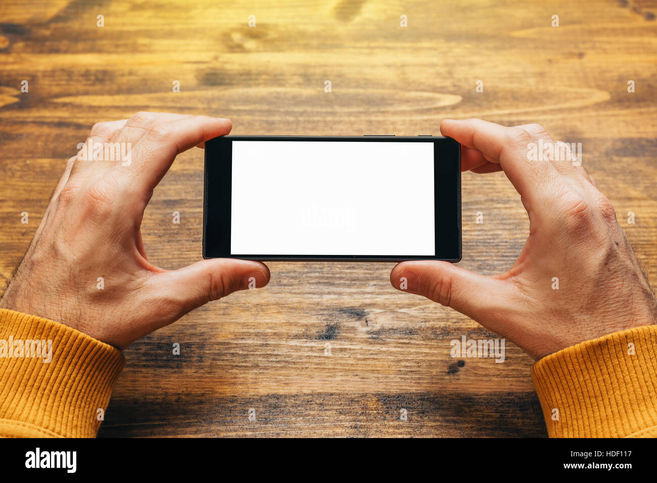 Uomo che utilizza smart phone in orizzontale con orientamento orizzontale per lo streaming di filmati o sfogliare foto gallery, schermo vuoto come spazio di copia Foto Stock