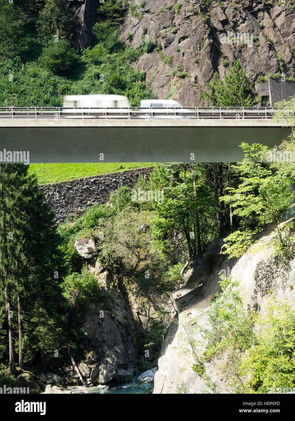 Una offuscata caravan è la guida su un ponte autostradale della Svizzera di autostrada A2 verso il tunnel del San Gottardo attraverso le alpi svizzere. Foto Stock