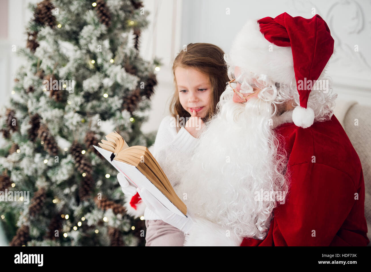 Bambino felice ragazza abbracciando Santa la lettura del libro e risate Foto Stock