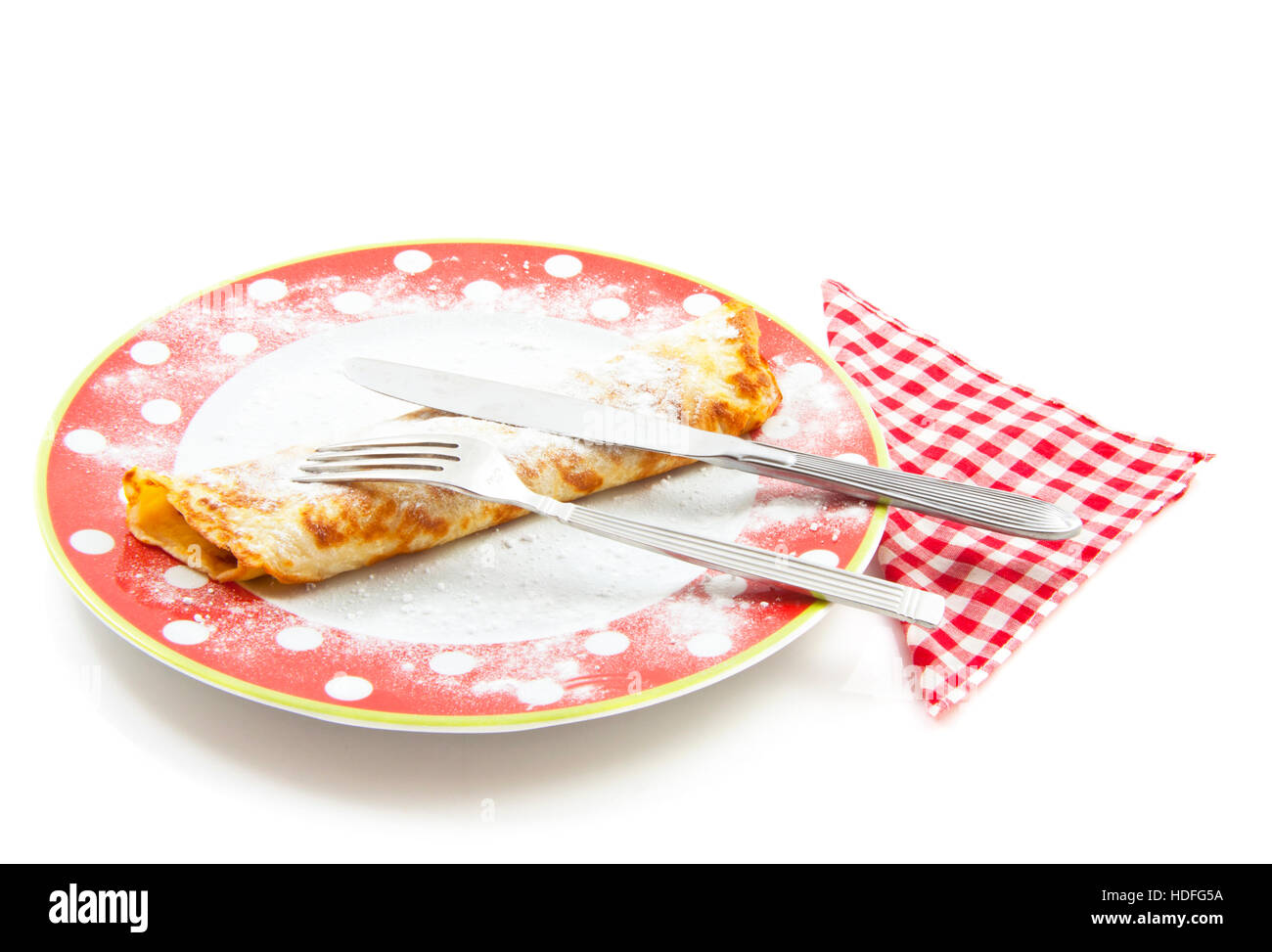 Pancake arrotolato sulla piastra macchiato con zucchero a velo e igienico isolato su bianco Foto Stock