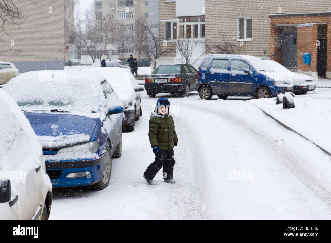 Inverno caldo vestito ragazzo giocando su una strada innevata Foto Stock