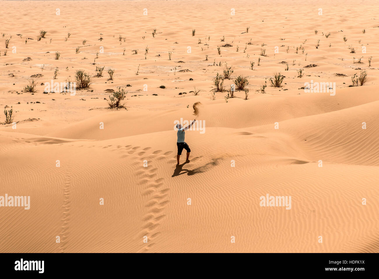 L'uomo turista nel deserto Rub al Khali in Oman gettando sabbia Foto Stock