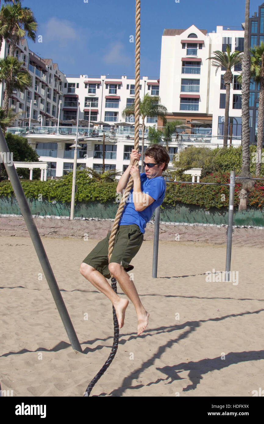 Giovane uomo corda di arrampicata sulla spiaggia di Santa Monica Beach California Foto Stock
