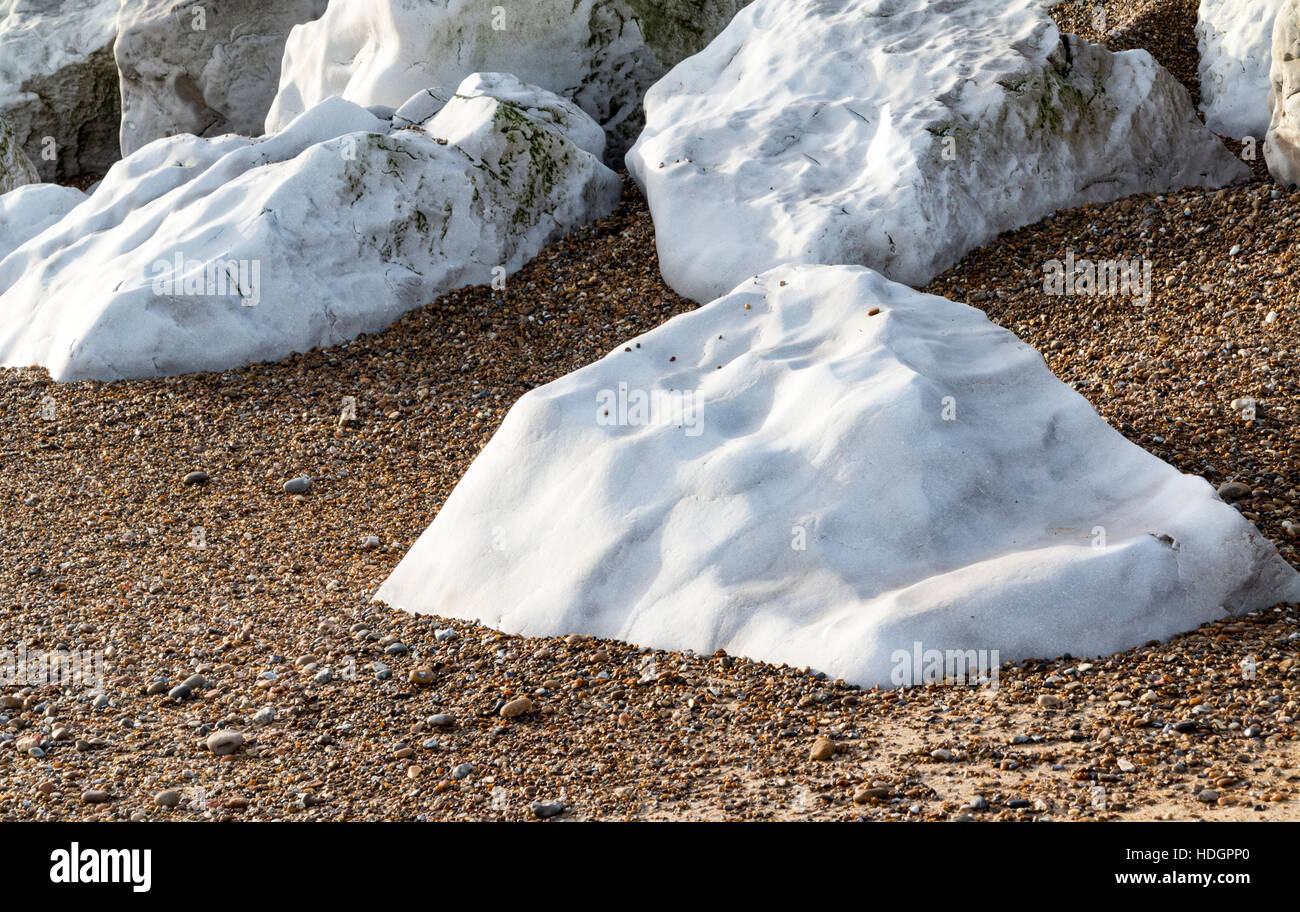 Difesa del Mare massi su una spiaggia di ciottoli splendidamente indossato e sagomato a onda e azione di ghiaia Foto Stock