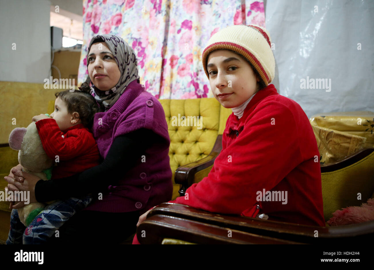 Rifugiato siriana Hanin Bathish Mtaweh, 13, con la sua madre Ibtissam, 43, e due anni di suor Amar nel seminterrato di un ex ski chalet blocco dove essi vivono sul monte Libano, appena a nord della capitale libanese, dopo la famiglia fuggì Siria cinque anni fa. Foto Stock