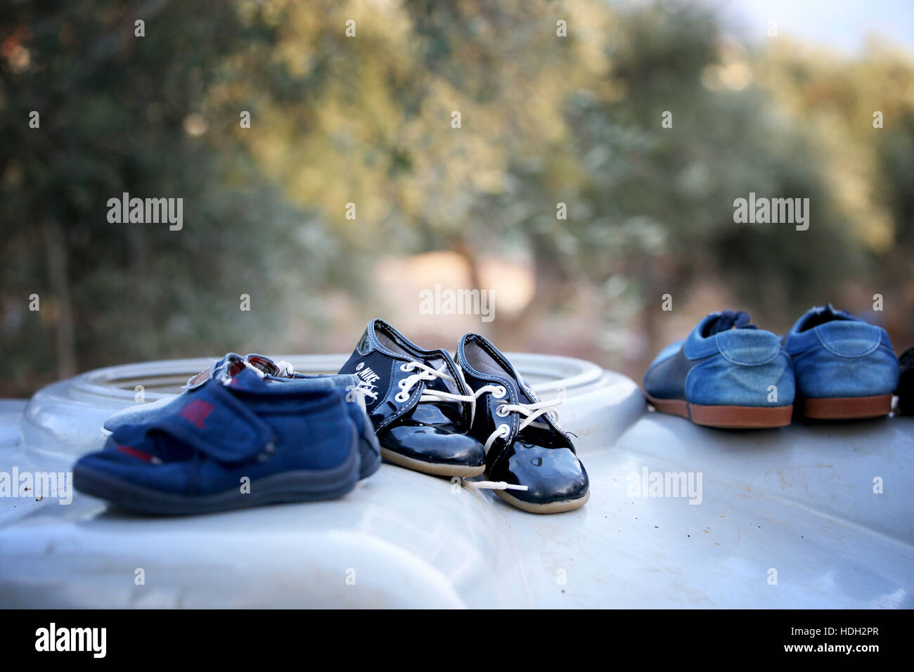 Calzature per bambini che sono stati puliti sono lasciate ad asciugare sulla parte superiore di un serbatoio di acqua in un campo di insediamento per rifugiati siriano situato in mezzo ad un oliveto di koura, vicino a Tripoli in Libano. Foto Stock