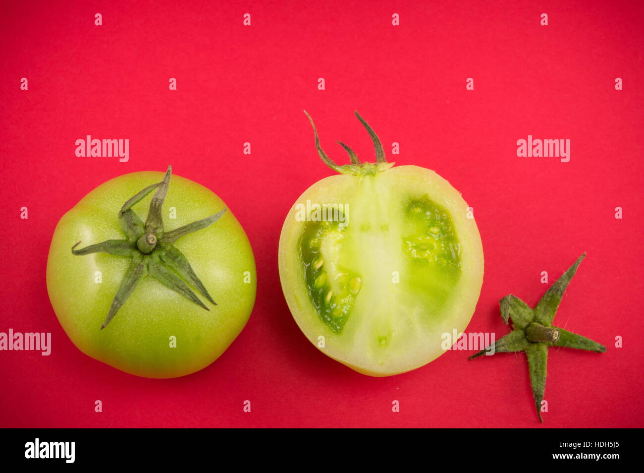 Crudo affettato i pomodori verdi sul rosso backgeround Foto Stock