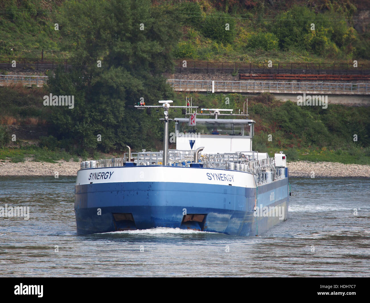 La nave "Synergy" (ENI 02334023) si vede navigare sul Reno a Oberwesel. Questa nave moderna fa parte delle operazioni navali contemporanee, che riflettono il ruolo dei fiumi nel commercio internazionale e nel trasporto in Europa. Foto Stock