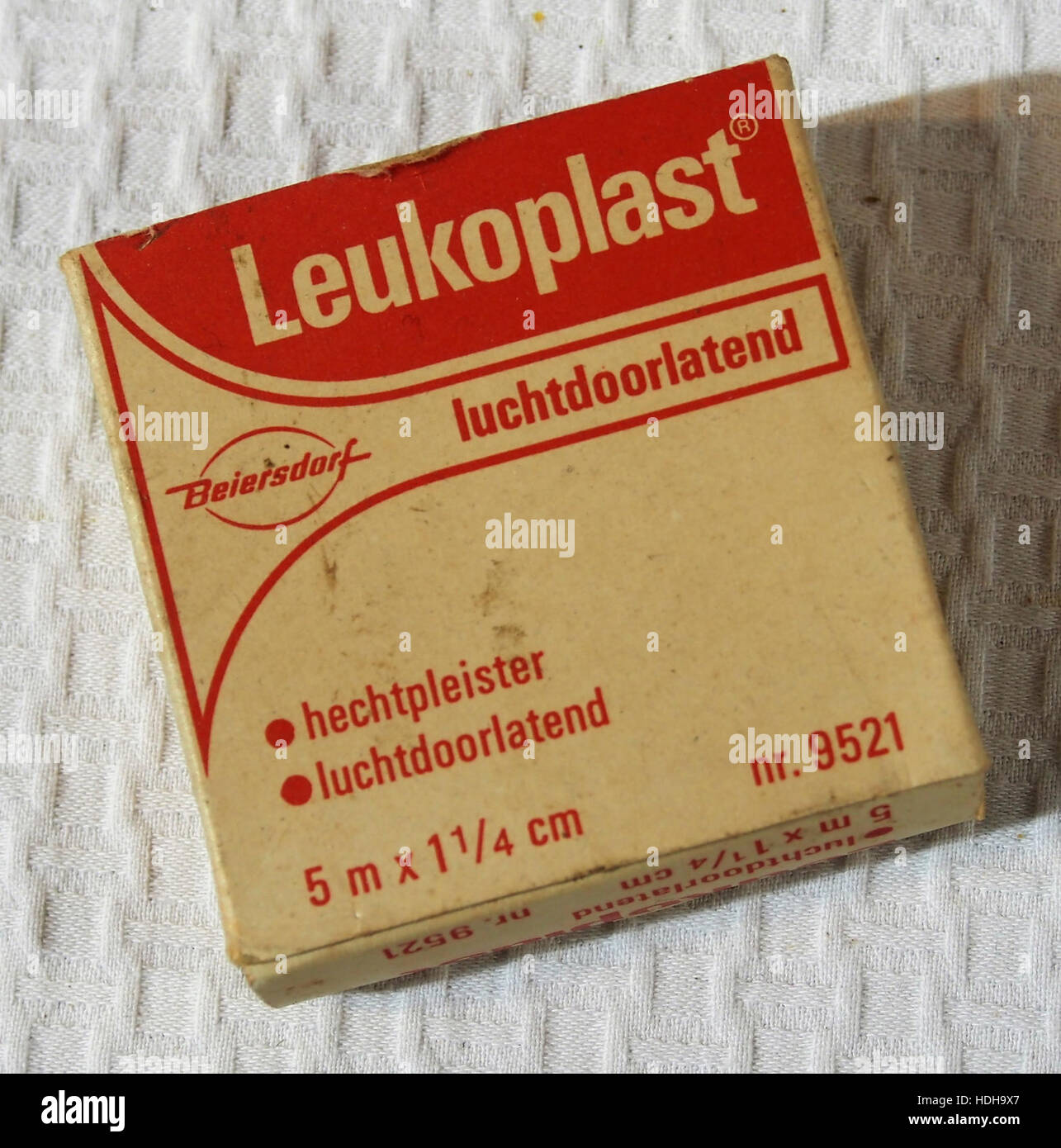 Questa immagine mostra la vecchia confezione di Leukoplast, un marchio noto per i suoi prodotti adesivi medici. La confezione riflette un design vintage, offrendo uno sguardo storico sul marketing e sulla presentazione del prodotto del marchio. Foto Stock