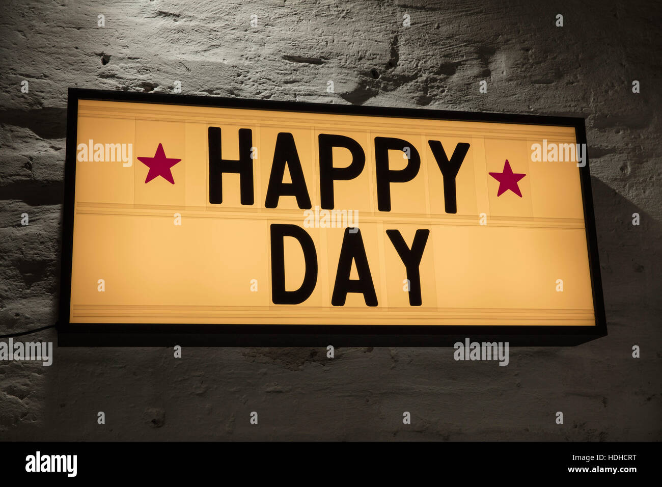 Close-up di felice giorno cartello contro il muro grigio Foto Stock