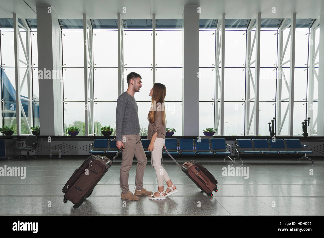 Lunghezza piena vista laterale della giovane coppia con bagagli guardando ogni altro all'aeroporto Foto Stock