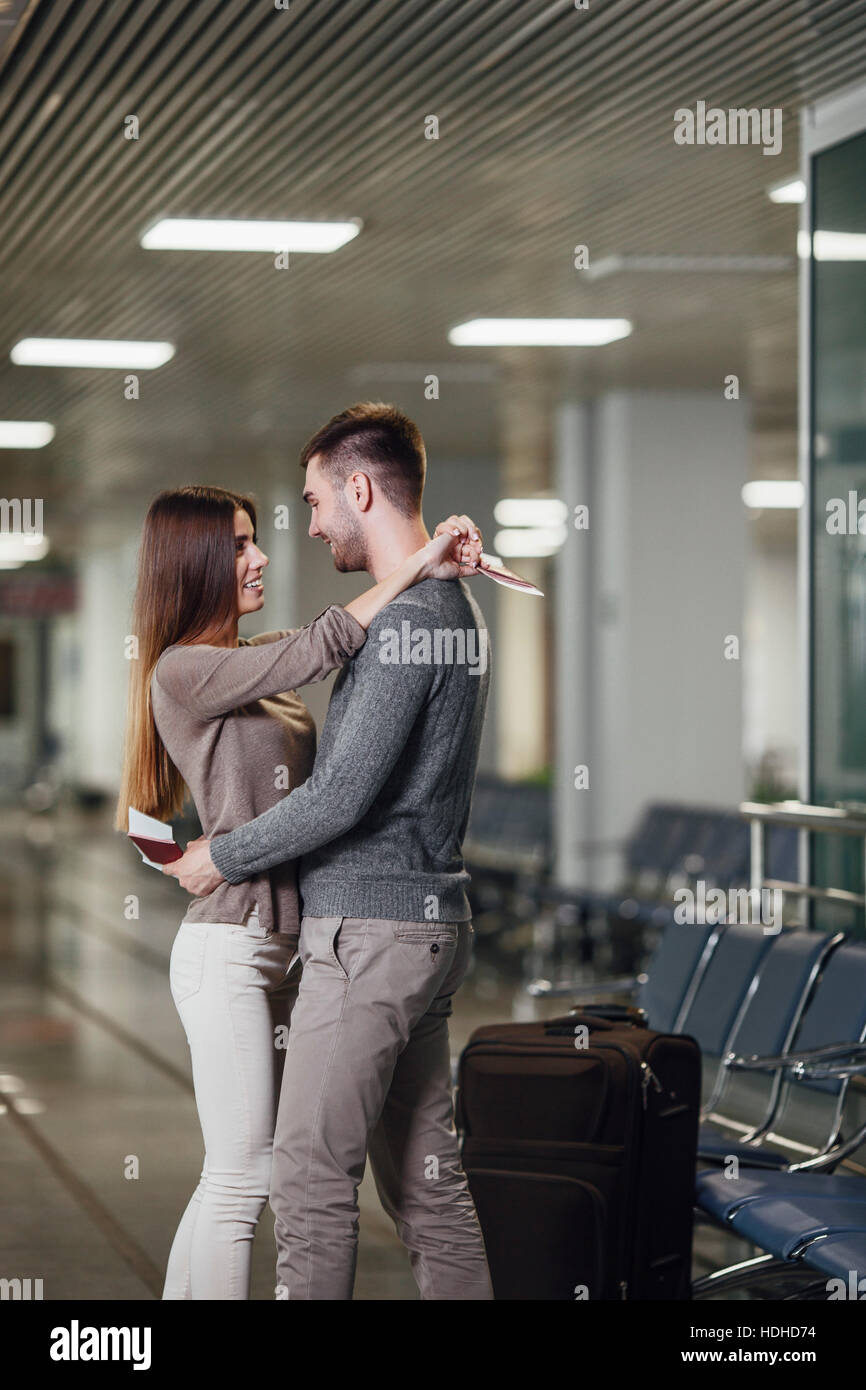 Vista laterale della romantica coppia giovane abbracciando in aeroporto Foto Stock