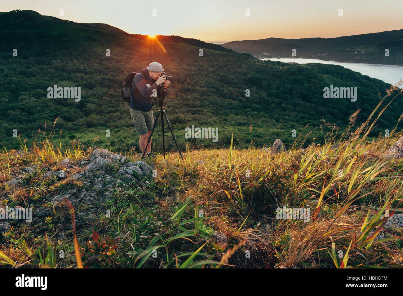 Uomo di fotografare sul campo erboso durante il tramonto Foto Stock
