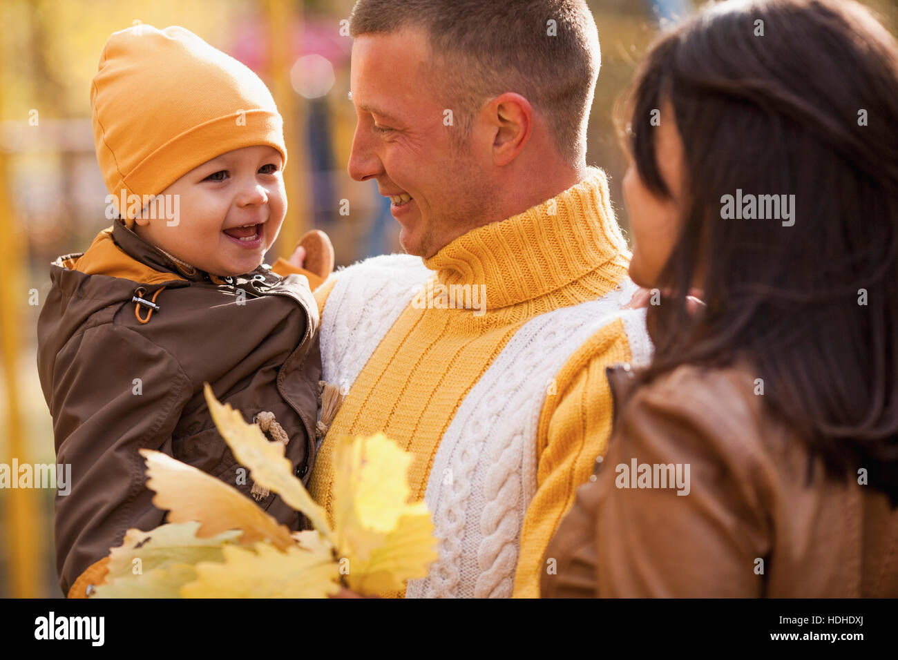 Allegro genitori guardando il figlio nel parco durante l'autunno Foto Stock