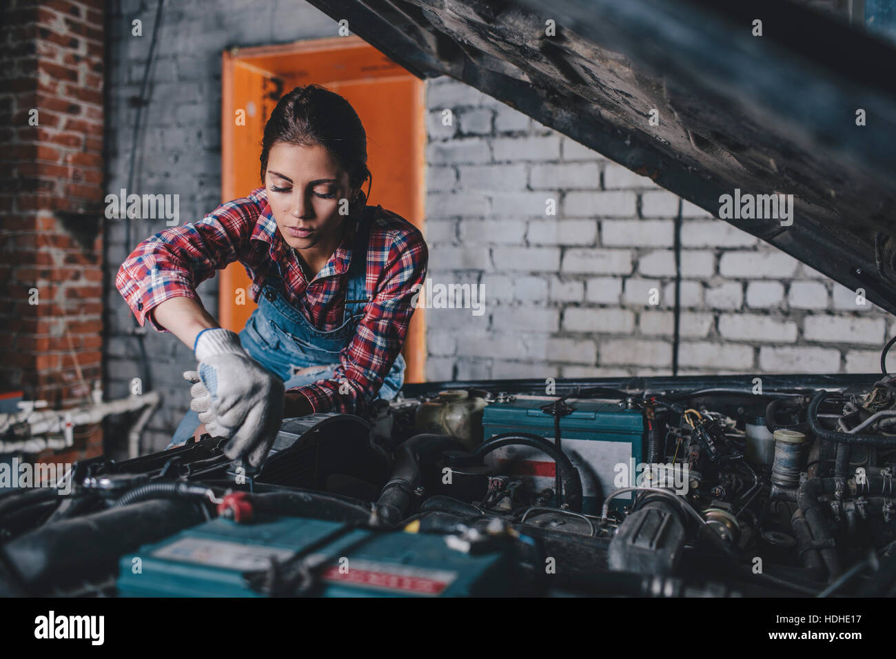 Meccanico femmina riparazione motore auto al garage Foto Stock